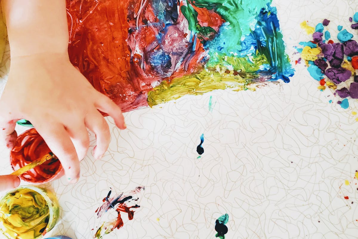 Mains d'un enfant peignant avec de la peinture colorée sur une feuille