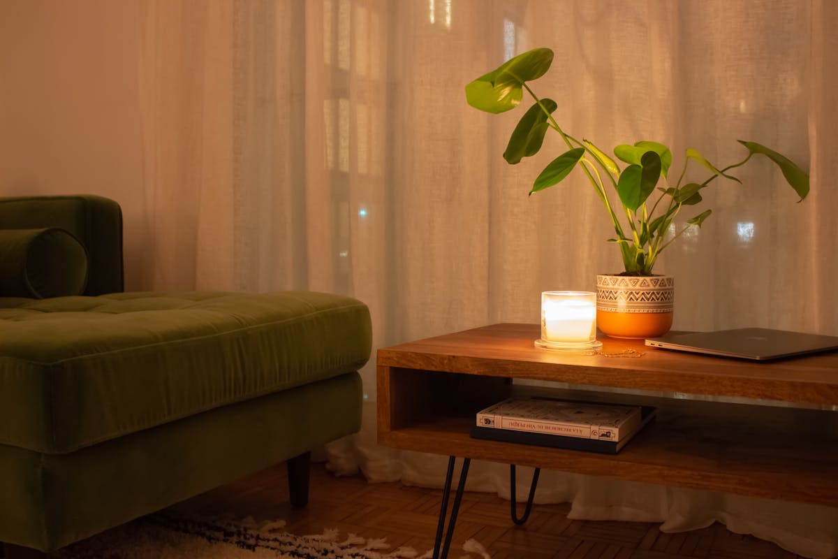 Salon cosy avec lumière chaude tamisée, bougies et plaids douillets