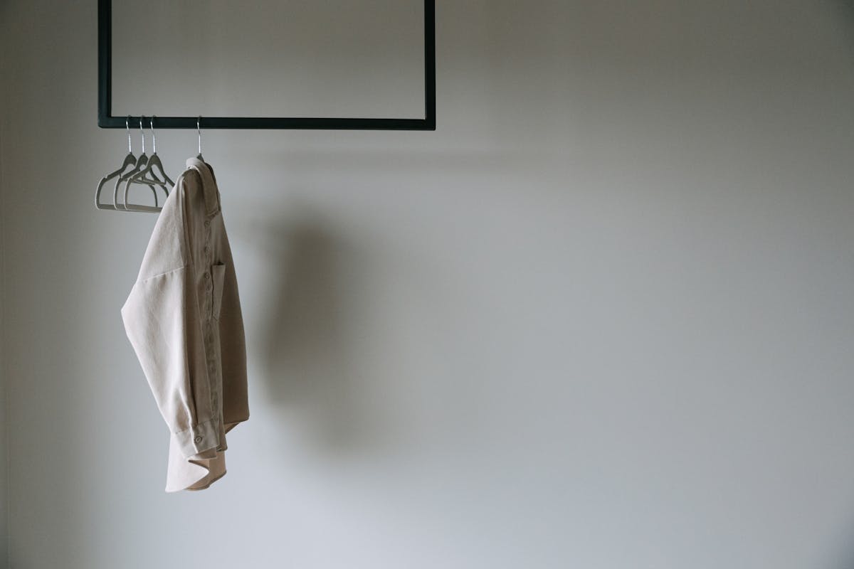 Veste beige élégante sur un portant minimaliste en métal, ambiance garde-robe épurée