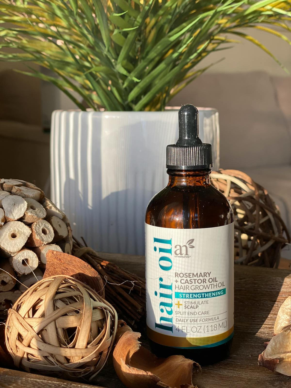 Flacon d'huile de ricin pour les cheveux posé sur fond naturel avec plantes