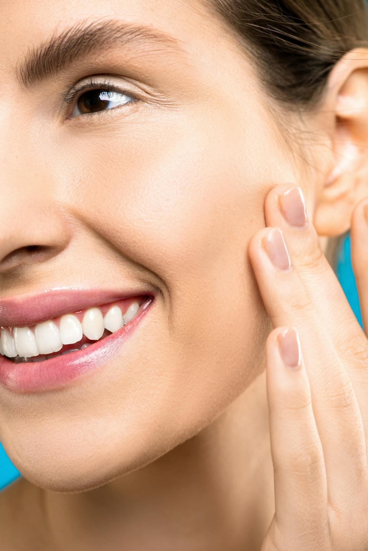 Femme à la peau ferme et lumineuse touchant son visage