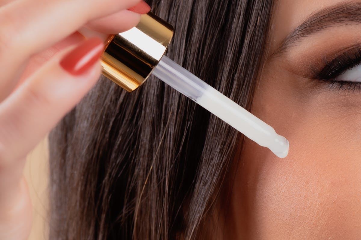 Femme appliquant un sérum cosmétique au compte-gouttes près du visage