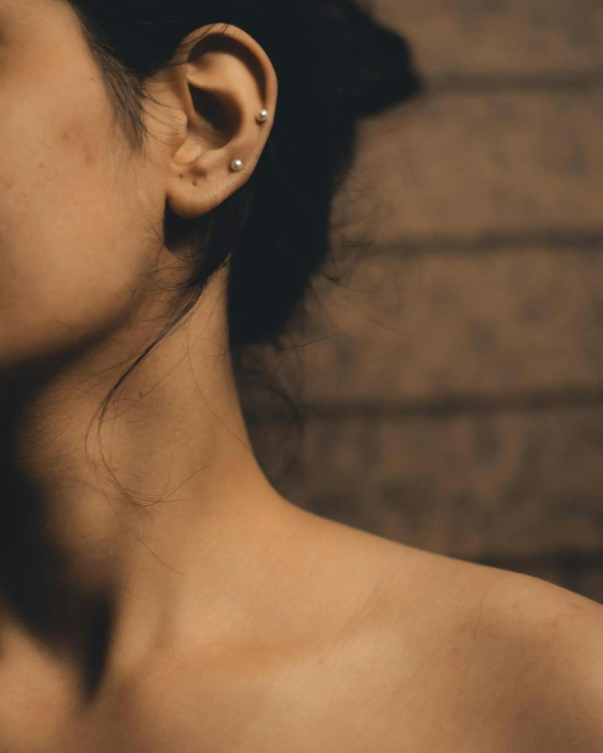 Oreille ornée de plusieurs piercings en or et titane