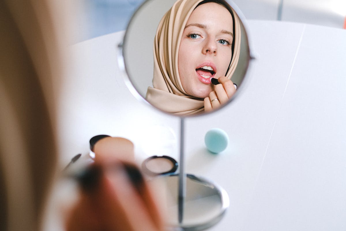 Femme se maquillant devant un miroir en pleine lumière
